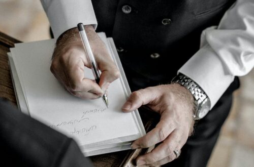 man in black suit writing on a white book